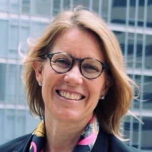 A blond woman wearing glasses and smiling at the camera